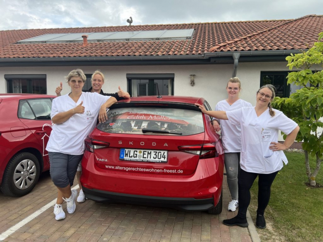 Vier Pflegekräfte vor einem Auto aus dem Fuhrpark der Häuslichen Krankenbetreuung Edith Müller GmbH
