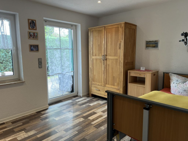 Blick in ein Pflegeapartment mit Bett und Schrank und Zugang zur Terasse