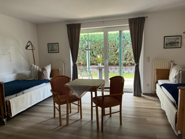 Freies Zweibettzimmer in Wohngemeinschaft mit Betten, Sitzecke und Blick in den Garten